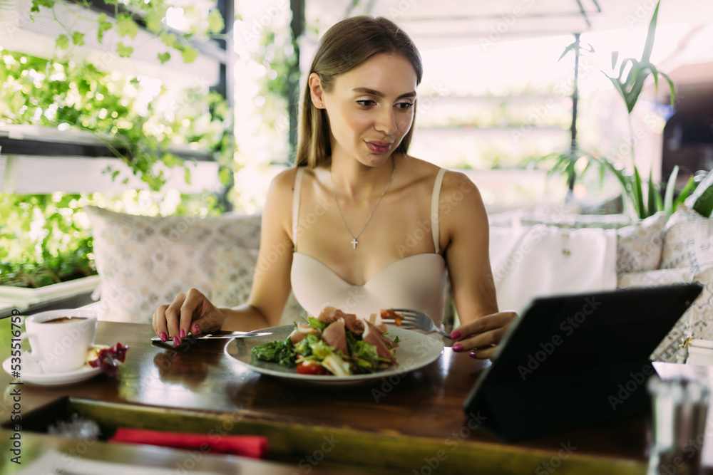 eating, technology, people and leisure concept - happy young woman with tablet p and food at restaurant
