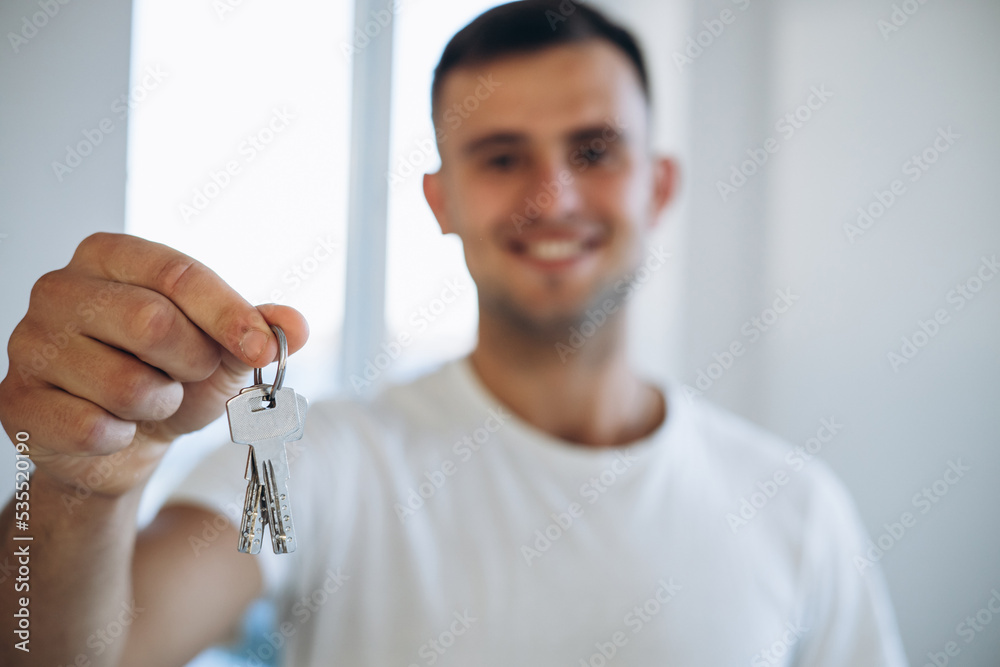 Young man holding keys from his new apartment Young man holding keys from his new apartment