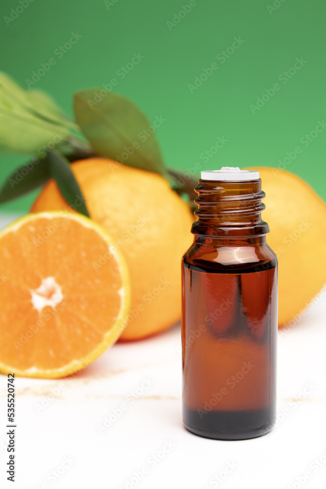 Natural organic orange essential oil for skin face and body health care. Moisturizing, aromatherapy, detox treatment, anti-stress effect. Fresh fruit, green leaves, green background Natural organic orange essential oil for skin face and body health care. Moisturizing, aromatherapy, detox treatment, anti-stress effect. Fresh fruit, green leaves, green background