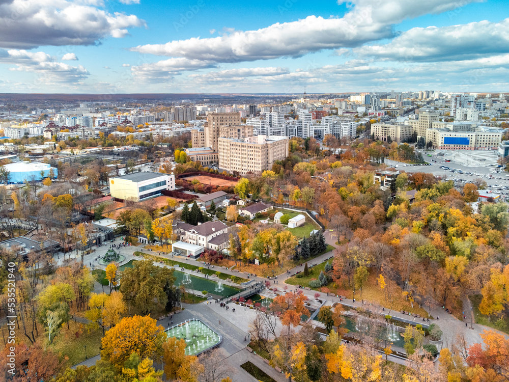 Aerial view on vibrant autumn Shevchenko City Garden with fountains near historical buildings. Tourist attraction in colorful park, rooftop in Kharkiv, Ukraine