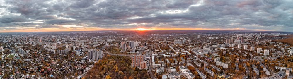 Aerial city panorama, vivid autumn sunset view with epic cloudscape. Botanical garden and Kharkiv city center. Residential district buildings in evening