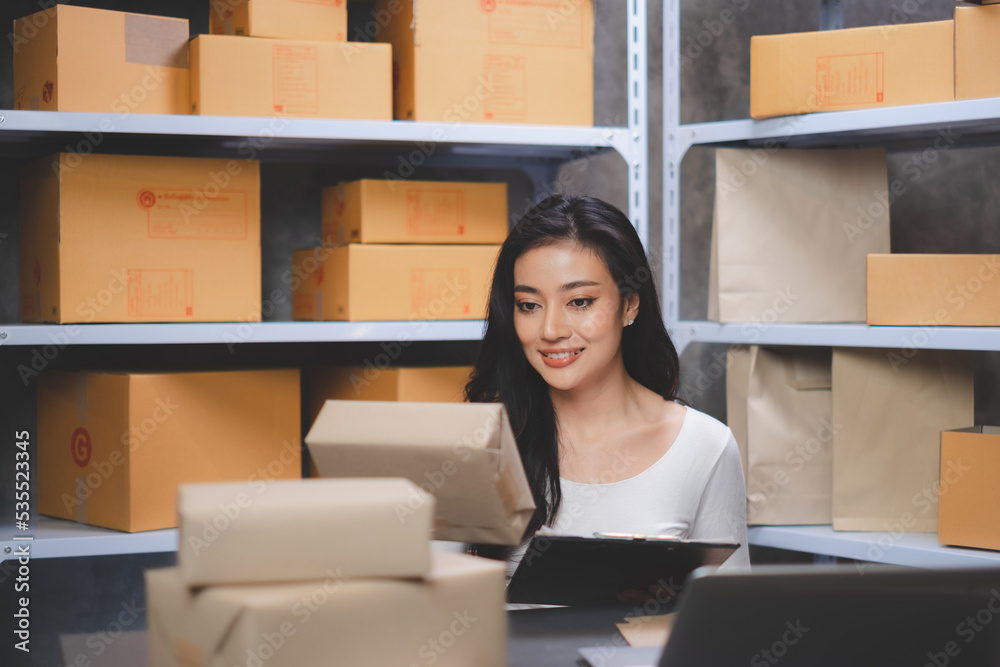 Asian Start-up businesswoman cheking serial number of boxes. Freelancers or saleswoman, is checking production orders. Entrepreneur SME working with box at home. Concept working at home. Asian Start-up businesswoman cheking serial number of boxes. Freelancers or saleswoman, is checking production orders. Entrepreneur SME working with box at home. Concept working at home.