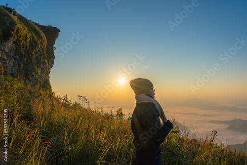 A women standing in front of a view background in the morning during gloden hour at Phu Chi Fa, Wiang Kaen, Chiang Rai, Thailand