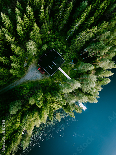 Aerial view of log cabin cottage in green summer woods by blue lake in Finland