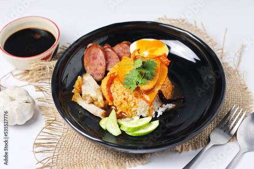 rice with roasted pork on top served with cucumber, boiled egg, crispy pork and bbq sauce that are sold in many places in Thailand.Barbecued red pork in sauce with rice is a popular food in Thailand.