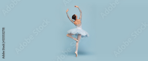 Fotografia Portrait of tender young ballerina dancing, performing isolated over blue studio background