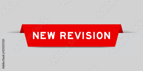 Red color inserted label with word new revision on gray background