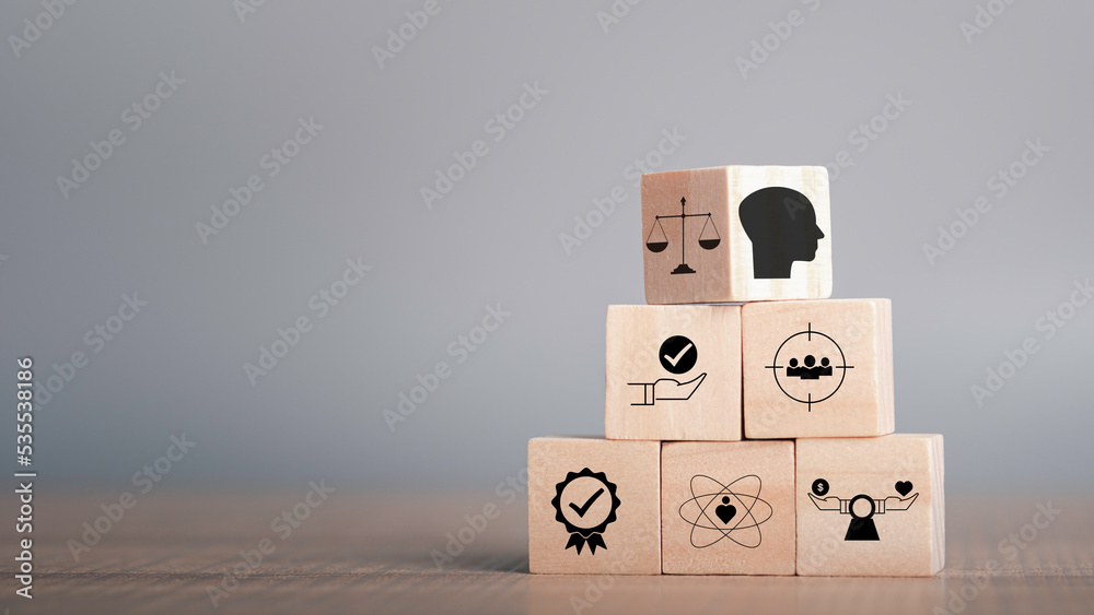 Ethics inside human mind, Business ethics concept. Ethics inside a head symbols in wooden cubes stacked on gray background with copy space. - obrazy, fototapety, plakaty 
