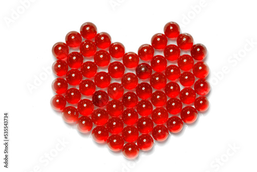 Decorative object on a light background. Heart from a small red glass ball