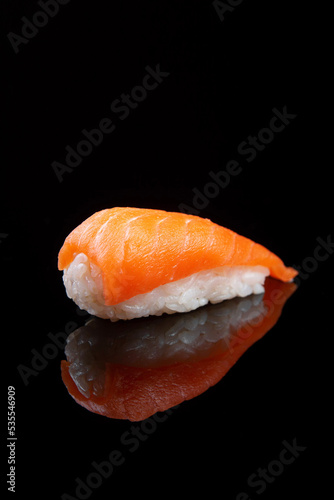 Sushi with rice and salmon on black background with reflection