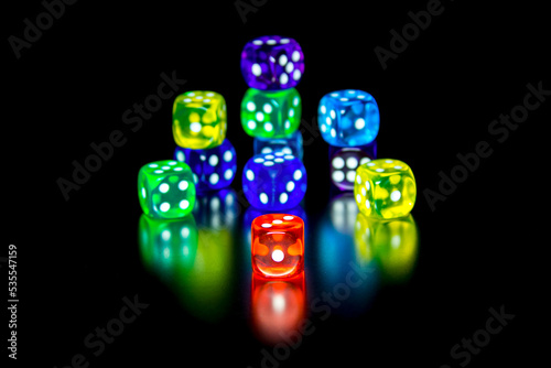 Multi-colored dice on a black background. Symbol of game and excitement