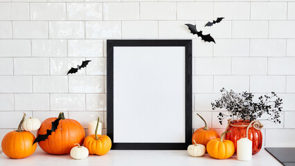 Black picture frame mockup with pumpkins, Halloween home decor, vase of flowers on table in scandinavian kitchen interior. Happy Halloween poster design.