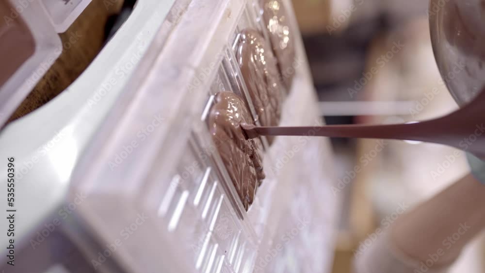 Crop chocolatier pouring melted chocolate into form in kitchen Crop chocolatier pouring melted chocolate into form in kitchen