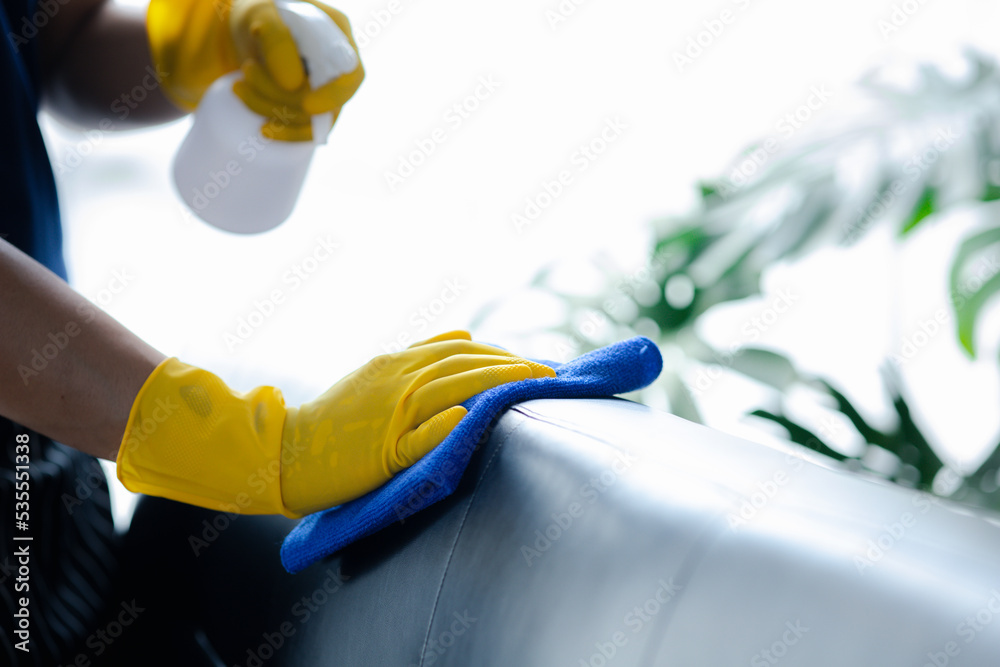 Person cleaning the room, cleaning staff is using cloth and spraying
