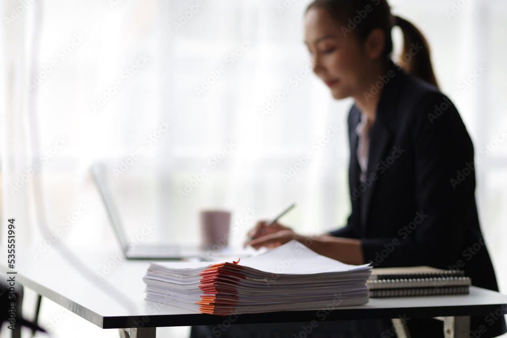 Business woman working on laptop and financial documents, female accountant in the office analyzes the budget using a calculator. Business woman working on laptop and financial documents, female accountant in the office analyzes the budget using a calculator.