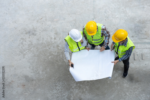 Top view of Asian engineer or Young Female Architect put on a helmet for safety and talk with a contractor on a construction building factory project, Concept of Teamwork, Leadership concept.