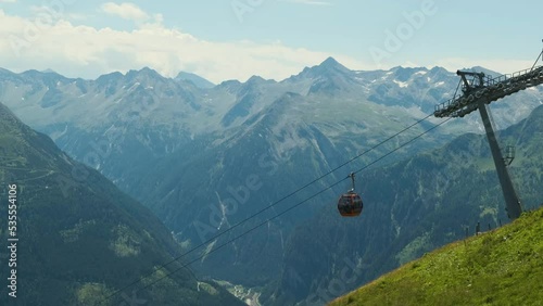 Modern tech Cable car, mountain gondola lift in the middle of beautiful Alps mountains on a summer day with snow on the peaks, green hills. Travel adventure landscape panorama vacation relaxing shot (ID: 535554106)
