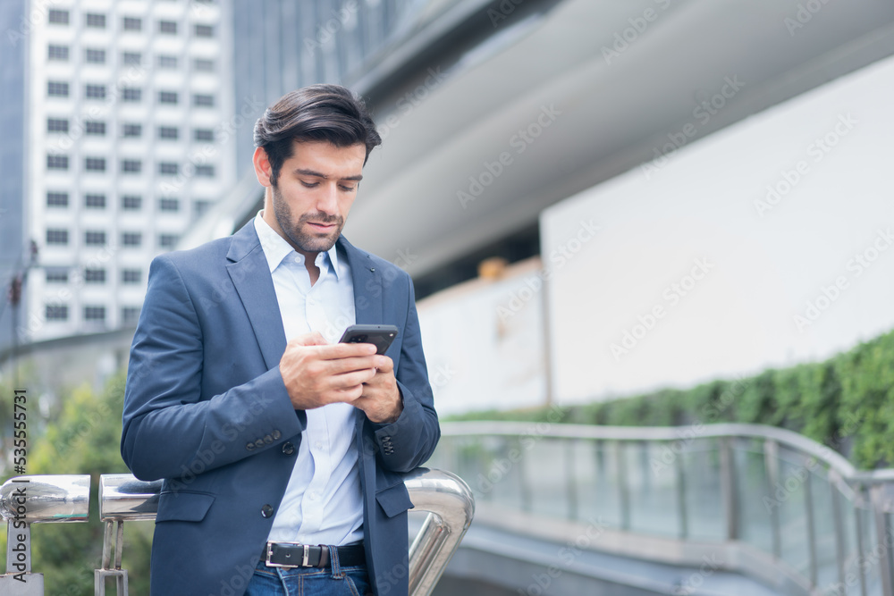 Urban business man talking on smart phone traveling walking at park . Casual young businessman wearing suit jacket . Handsome male model . Urban business man talking on smart phone traveling walking at park . Casual young businessman wearing suit jacket . Handsome male model .