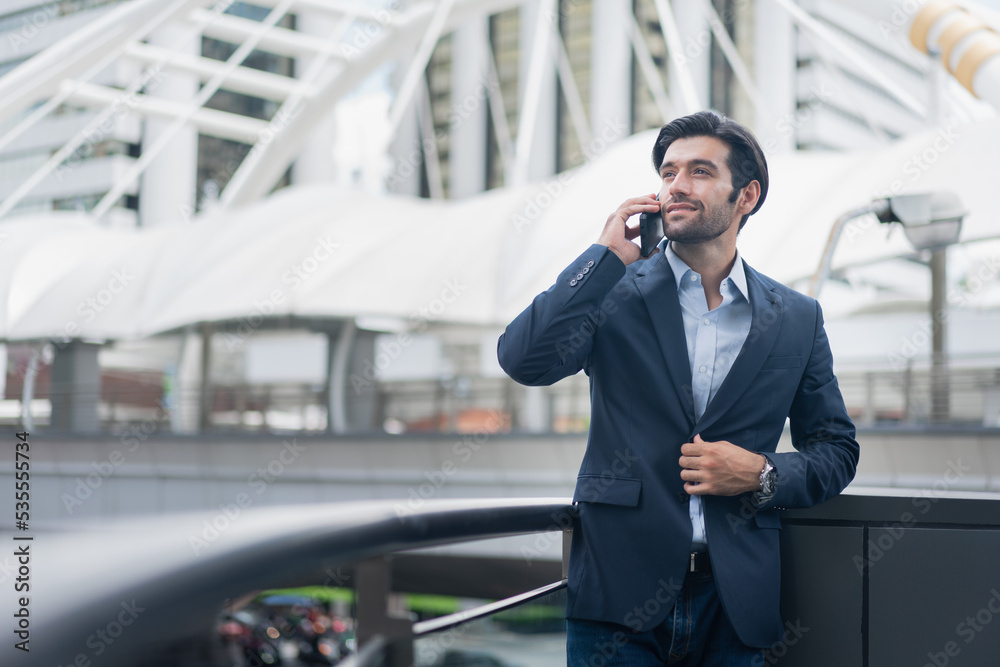 Urban business man talking on smart phone traveling walking at park . Casual young businessman wearing suit jacket . Handsome male model . Urban business man talking on smart phone traveling walking at park . Casual young businessman wearing suit jacket . Handsome male model .