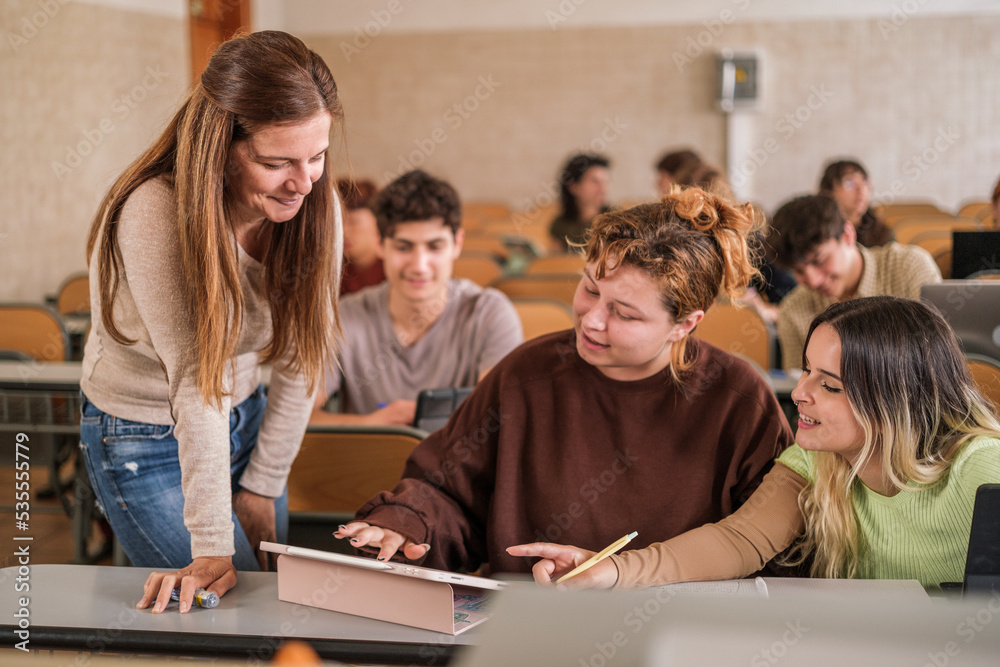 University professor solving the doubts of her students in the multicultural classroom University professor solving the doubts of her students in the multicultural classroom