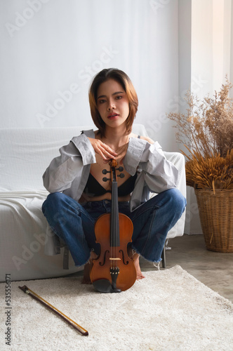 Young beautiful lady squart down nd put violin,in front of her body,looking with romantic emotion, photo