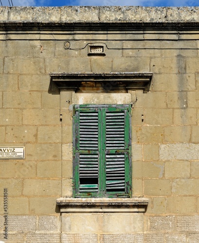 Closed window of the old building covered by green wooden blinds in Rabat town on Malta