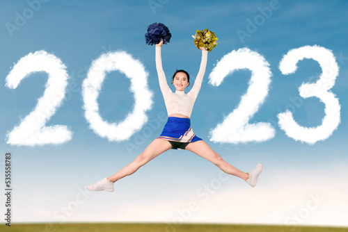 Beautiful cheerleader girl jumping with 2023 number