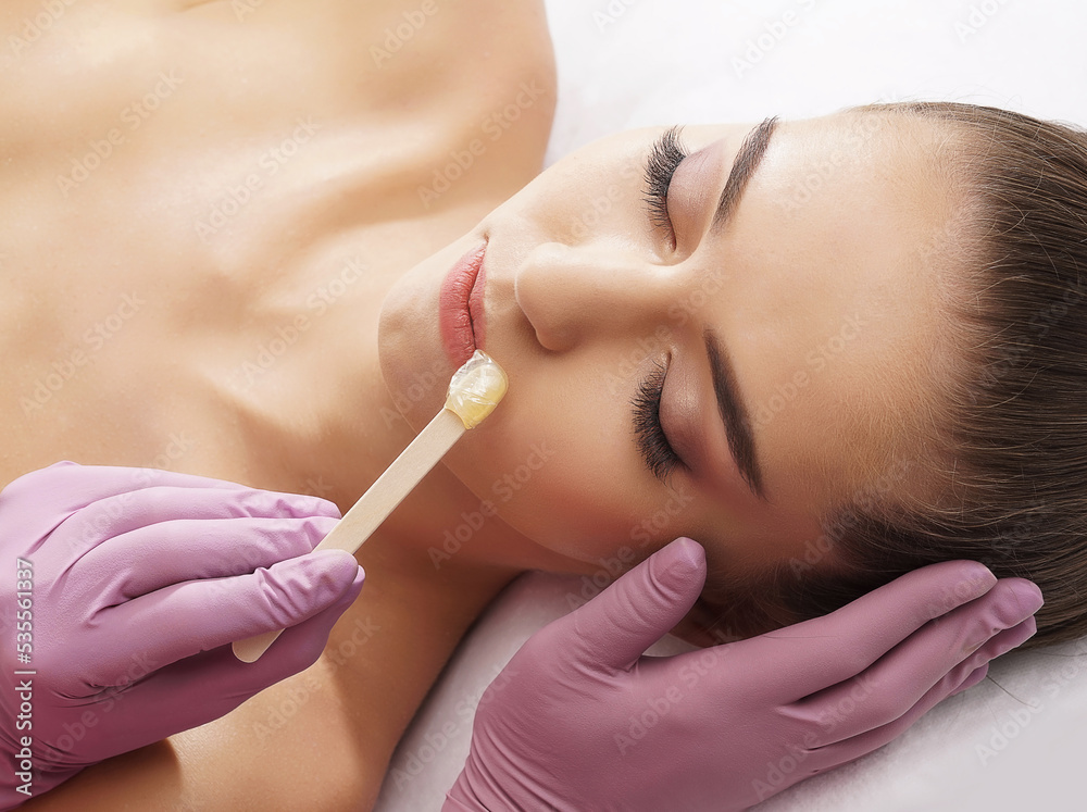 Hair removal, beauty and health concept. A young girl is getting an epilation procedure. A processional beauty worker is making depilation with hot wax. Hair removal, beauty and health concept. A young girl is getting an epilation procedure. A processional beauty worker is making depilation with hot wax.