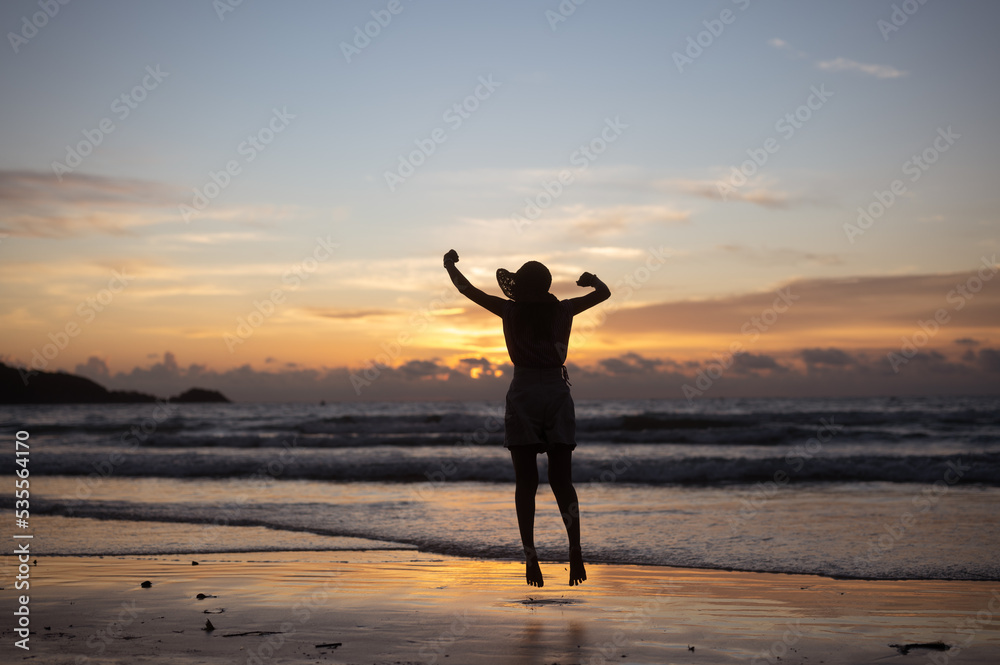 Silhouette of woman in hat on Enjoying Beautiful Sunset on the Beach