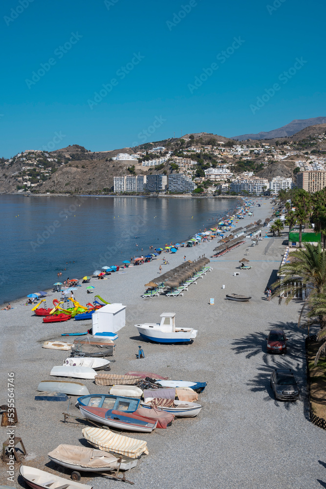 Disparo vertical de la playa de Almuñecar con barcas, sombrillas y turistas, España
