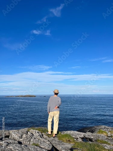 Human silhouette standing in front of the sea, looking at the sea horizon, blue sky 