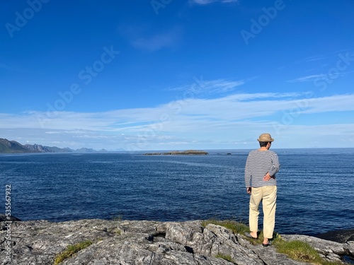 Human silhouette standing in front of the sea, looking at the sea horizon, blue sky 