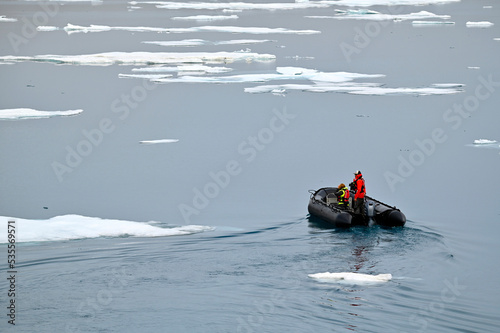 Zodiac boat making its way through the Arctic sea with a floe of melting ice, against picturesque seascape