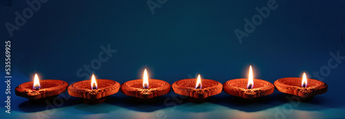 Diwali, Deepavali Hindu festival of lights. Diya lamp lit on blue, close up