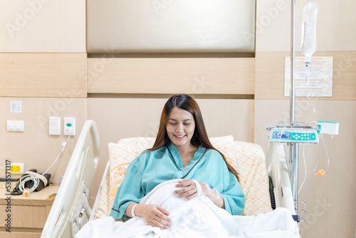 Asian Patient woman saline intake in hospital  Beautiful woman with patient dress  smile get well sitting on patient bed in hospital  Saline bottle hanging  smile feedback of patient.