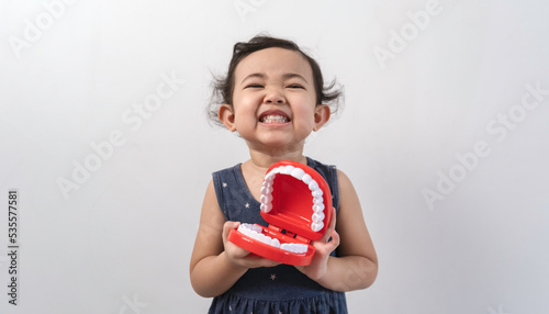 Little cute funny asian girl holding tooth jaw.Kid training oral hygiene. Child learning brushing, cleaning teeth. Prevention of caries in children. children dentistry. dental care kids