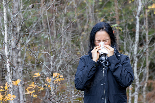 woman sneezes outdoors