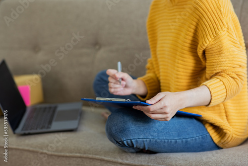 person typing on a laptop sitting on the sofa in living room.