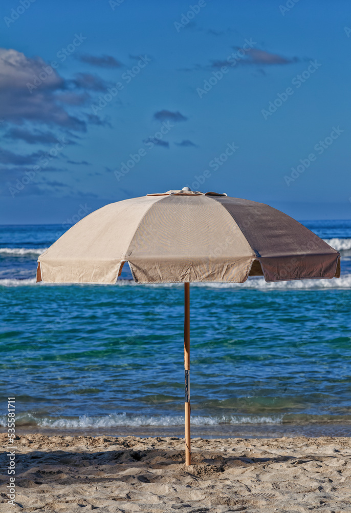 Tan Beach Umbrella with an Ocean Background.