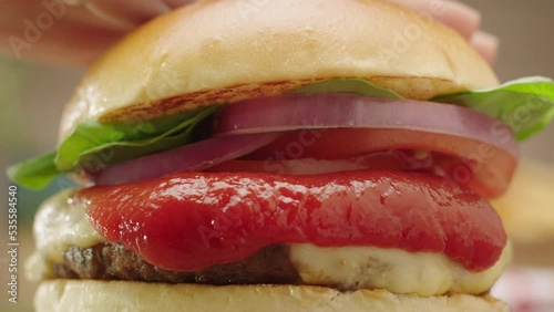 delicious cheeseburger being smashed with dripping ketchup in slow motion with zoom in
