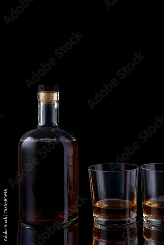 bottle of strong alcohol brandy with glasses on black background