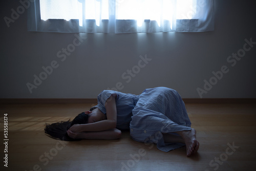 自室でうずくまる女性のイメージ © sho987i