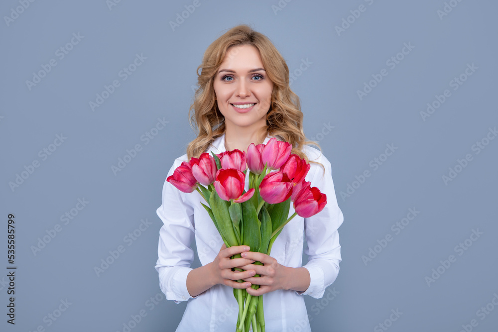 smiling blond woman with spring tulip flowers on grey background smiling blond woman with spring tulip flowers on grey background