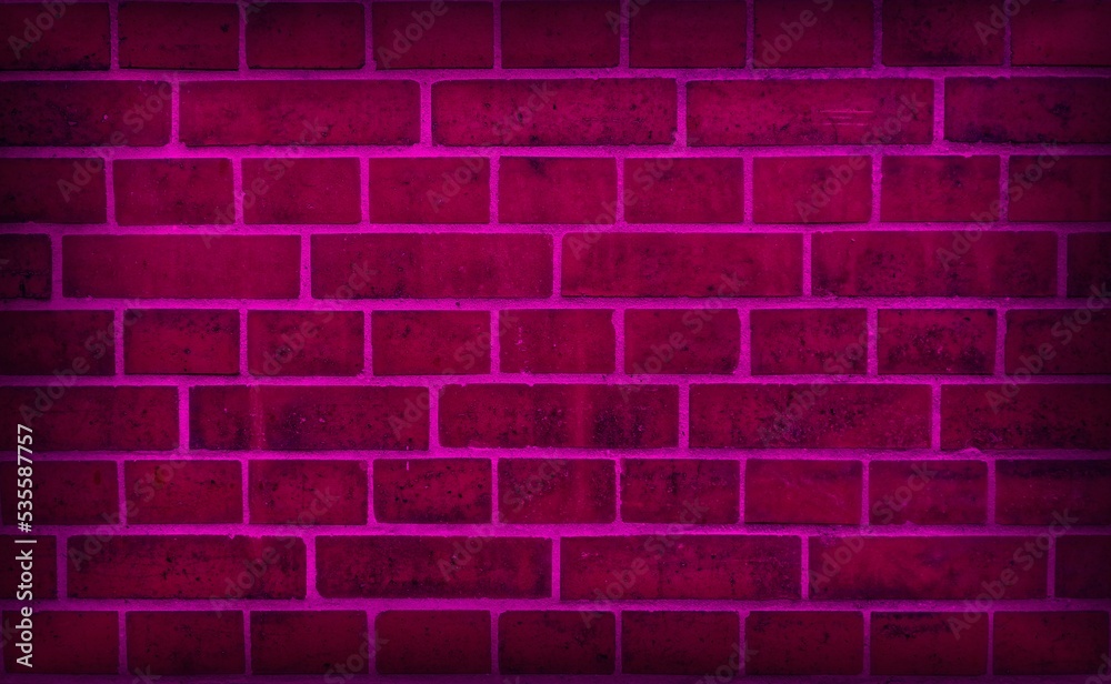 Naklejka premium Neon light on an old brick wall. pink grunge background. Light effect
