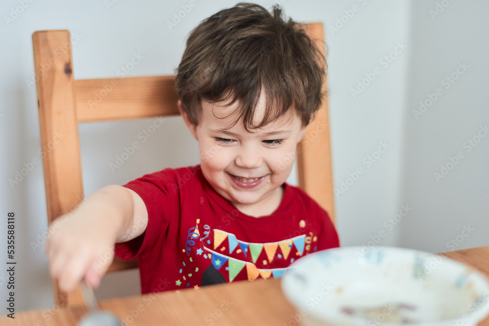 a boy is having fun at the breakfast table eating oatmeal a boy is having fun at the breakfast table eating oatmeal
