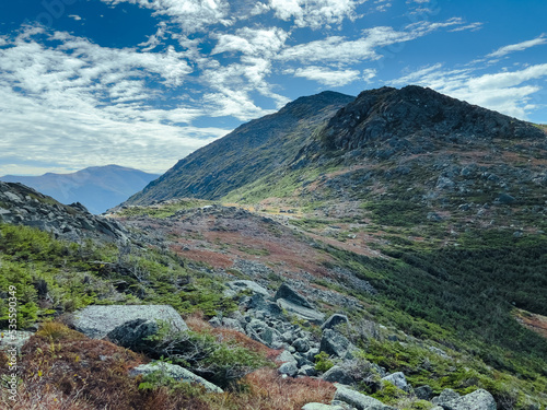 Large, rocky mountains in the sky above a dense and lush forest. These are mountains in the Presidential Range of the White Mountains of New Hampshire. Mt Adams, Mt Madison and Mt Washington.