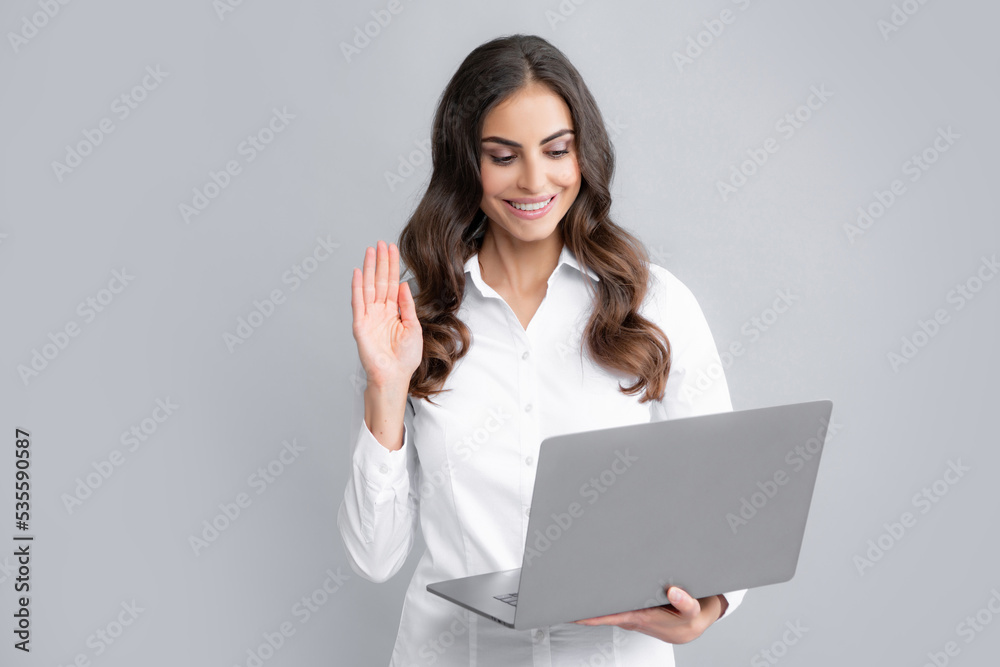 Portrait of a cheerful young casual girl standing isolated over gray background, using laptop computer. Business woman at work. Portrait of a cheerful young casual girl standing isolated over gray background, using laptop computer. Business woman at work.