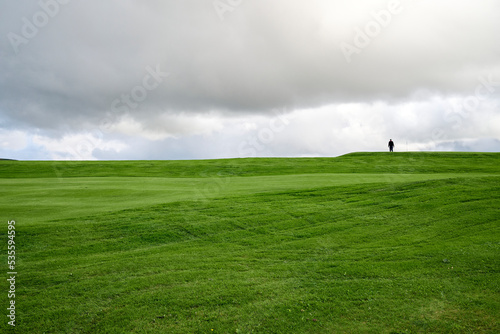 Unrecognizable traveler walking on green meadow