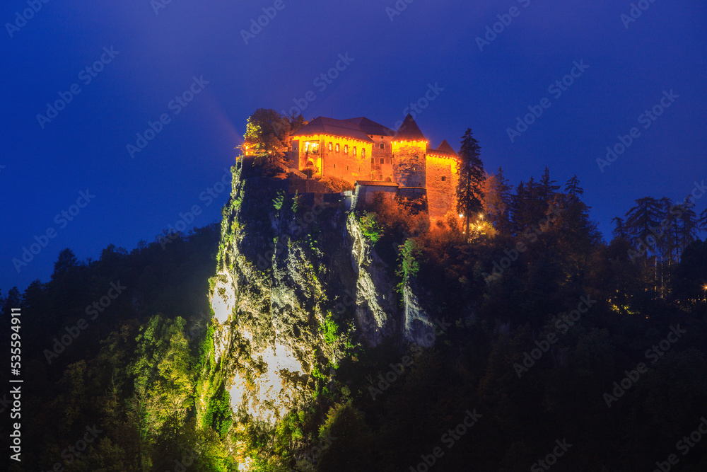 illuminated castle on Lake Bled in fog at dawn