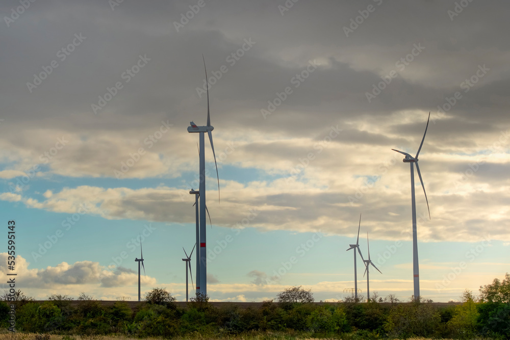 Wind turbines generate green energy in a field at sunset
